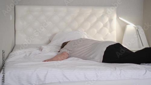 A tired elderly woman falls flat on her bed