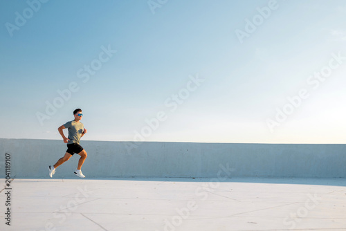 Cuadro en lienzo Runner sprints joyfully under a bright sky on a sunny rooftop at midday