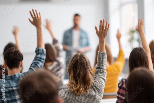 Group of Students Raise Their Hands in a Modern Classroom With a Teacher at the Front Giving Directions