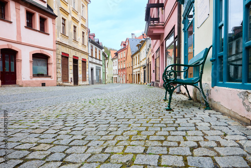 Empty cobblestone street with colorful houses and bench
