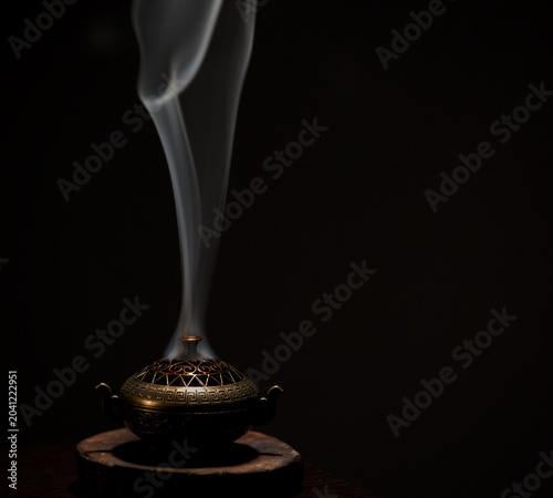 Incense aroma sticks in vintage box with white texture smoke on black background with copy space