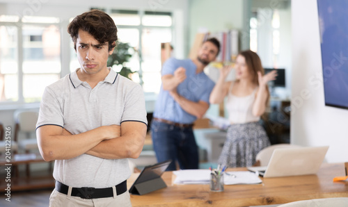 Foto Oppressed male office employee is ridiculed, reproached, and humiliated by colleagues