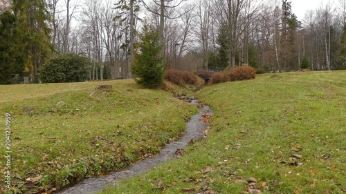 beautiful girl in a pink jacket jumps over a small stream in the autumn city park