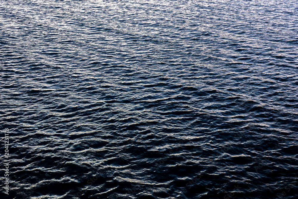Obraz premium Deep blue ocean texture with cold evening light. Rhythmic sea waves pattern.
