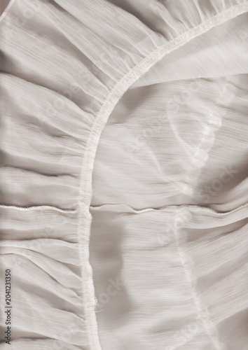 Soft lace fabric with delicate folds on white surface under soft light