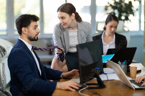 Bild auf Leinwand Young woman sits at office desk, flirting with her male colleague with playful s