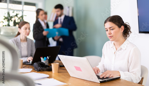 Fotografi Young woman is a qualified specialist, works in a modern office, she types on a laptop, analyzes the company budget and plans investments