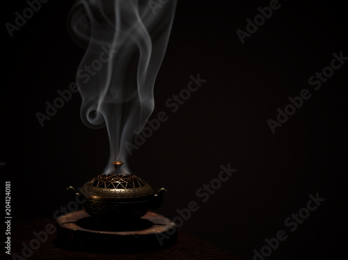 Incense aroma sticks in vintage box with white texture smoke on black background with copy space