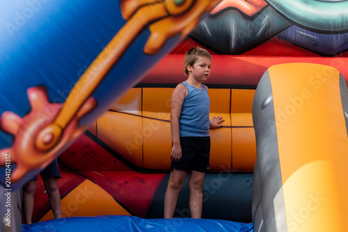 Tableau sur toile Child enjoys playtime on colorful inflatable obstacle course during sunny day ou
