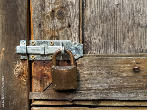 Vászonkép Old metal padlock attached to a wooden door latch on a rustic farm building