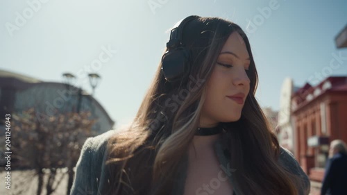 Sunlit redbrick street portrait of woman pointing and gesturing, headphones and coat, expressive profile and candid closeups editorial vibe, empowered and playful mood, warm highlights and crisp