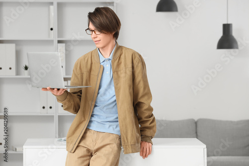 Portrait of young man in eyeglasses working with laptop at office