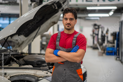 Confident mechanic standing in car repair shop