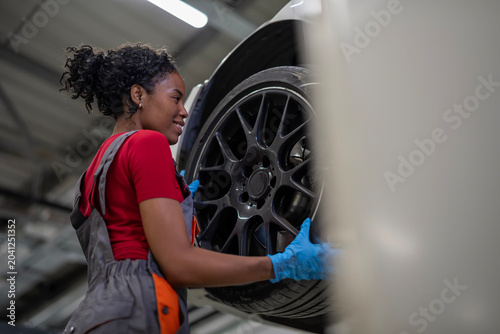 Female mechanic installing car wheel in garage