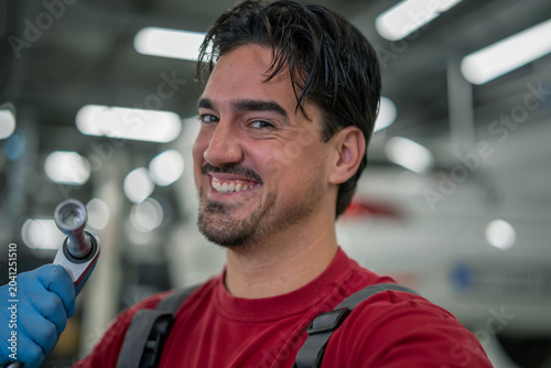 Foto Smiling mechanic holding wrench tool in garage