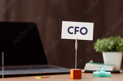 Eye-catching image of CFO text on card. The word stands for Chief Financial Officer. Shown with laptop, clips.