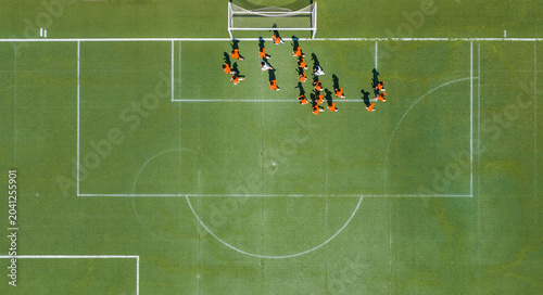 Aerial view of children in orange jerseys running across the soccer field during soccer practice at a sports park in Wuhan, China.