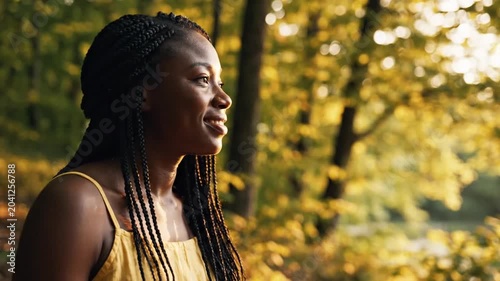 Young Black woman using smartphone on wooden table outdoors