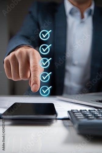 Businessman pointing at a checklist with checkmarks on a digital interface.