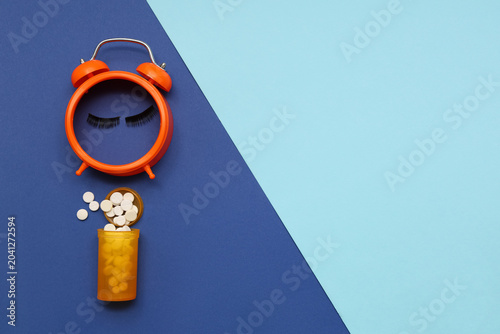 Quadro su tela Alarm clock with lashes and sleeping pills on blue background