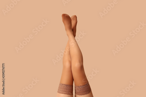 Fotografía Legs of beautiful woman in stockings on beige background