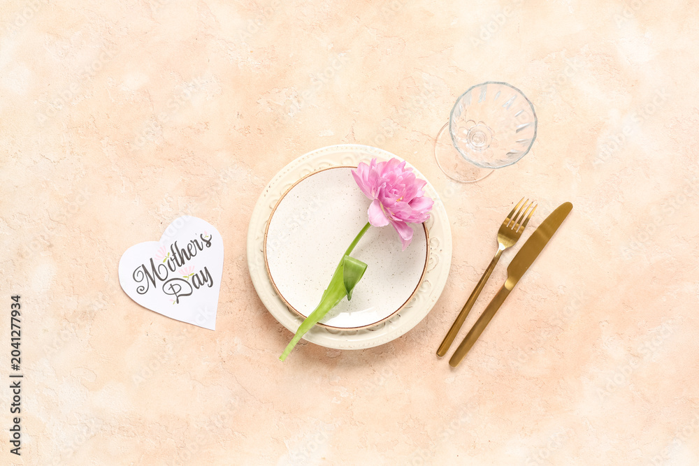 Naklejka premium Table setting with greeting card for Mother's day and flower on beige background