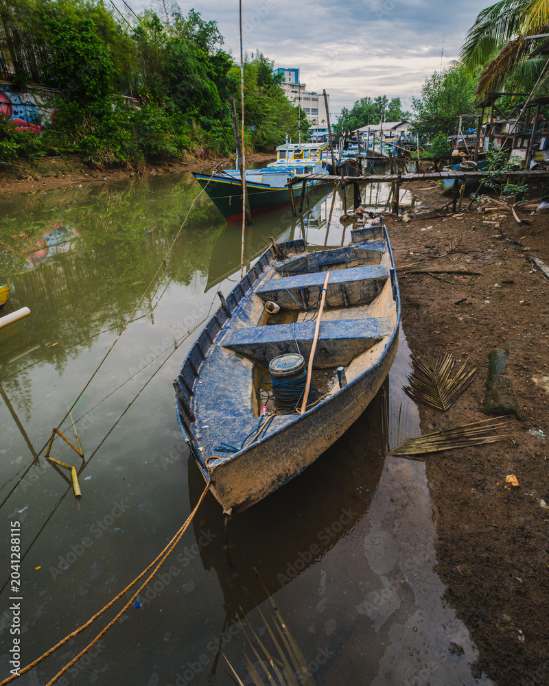 Obraz premium Blue Wooden Fishing Boat Anchored in a Muddy Canal.