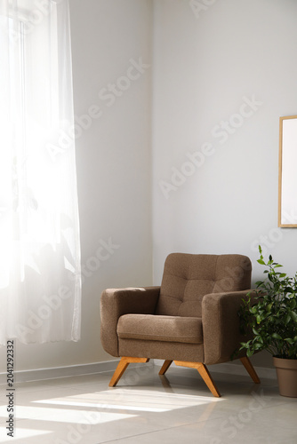 Fotografía Cozy brown armchair and houseplant near window