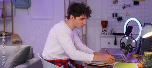 Male student studying at home in evening