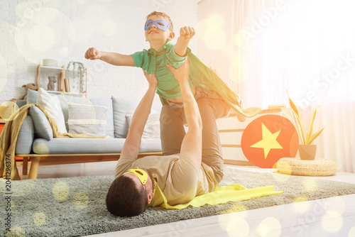 Little boy with his father in superhero costumes playing at home