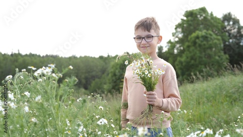 Valokuva Young boy wearing glasses and a light colored sweatshirt, standing in a sunny me