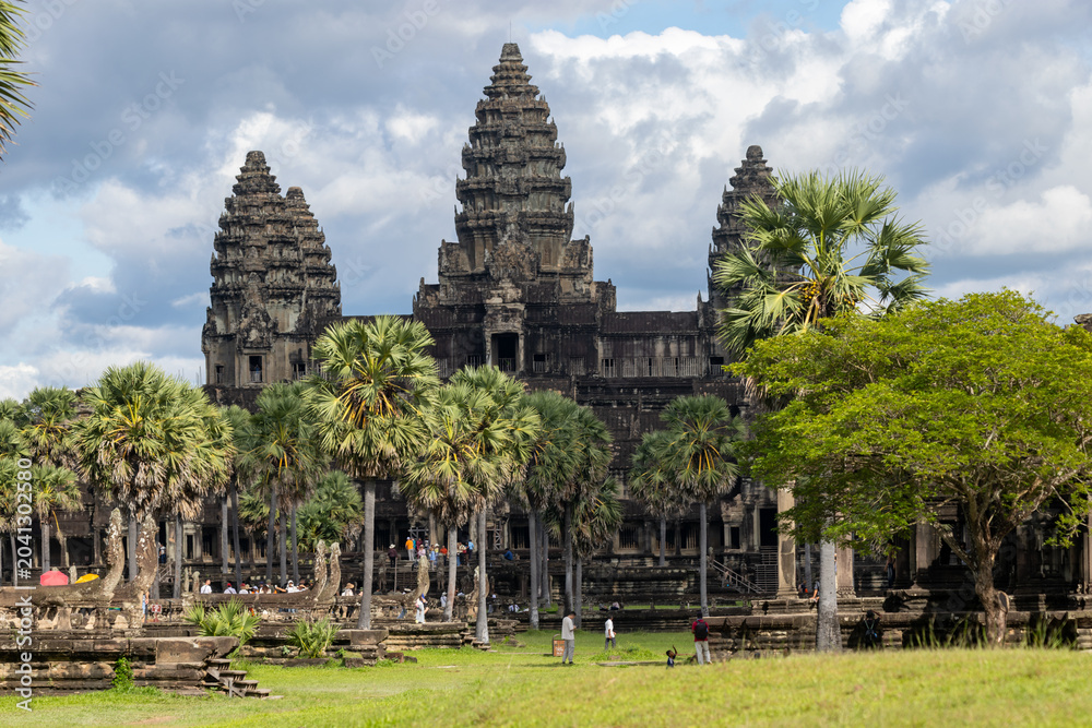 Fototapeta premium Angkor Wat, Siem Reap, Cambodia. Tourists explore the ancient temple complex, a UNESCO World Heritage site, on a cloudy day.
