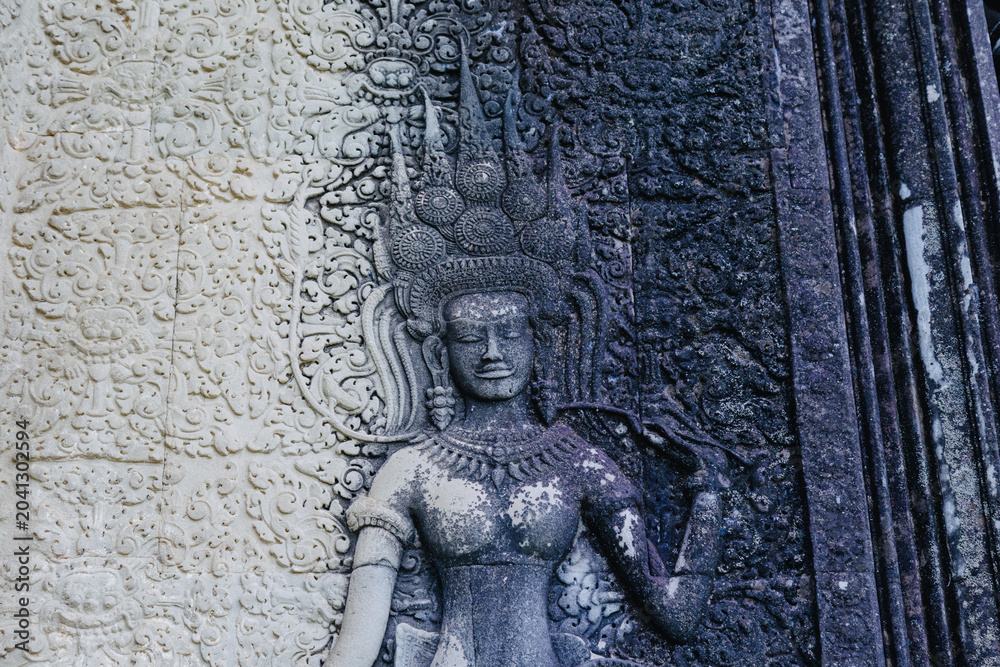 Naklejka premium Apsara dancer carving on the ancient temple walls of Angkor Wat, Siem Reap, Cambodia. These celestial dancers are a common motif in Khmer art.