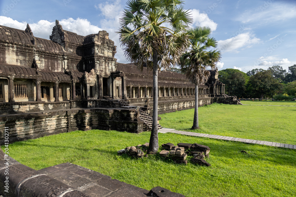 Naklejka premium Angkor Wat, Siem Reap, Cambodia. The iconic temple complex, a UNESCO World Heritage site, is bathed in sunlight under a blue sky with scattered clouds.