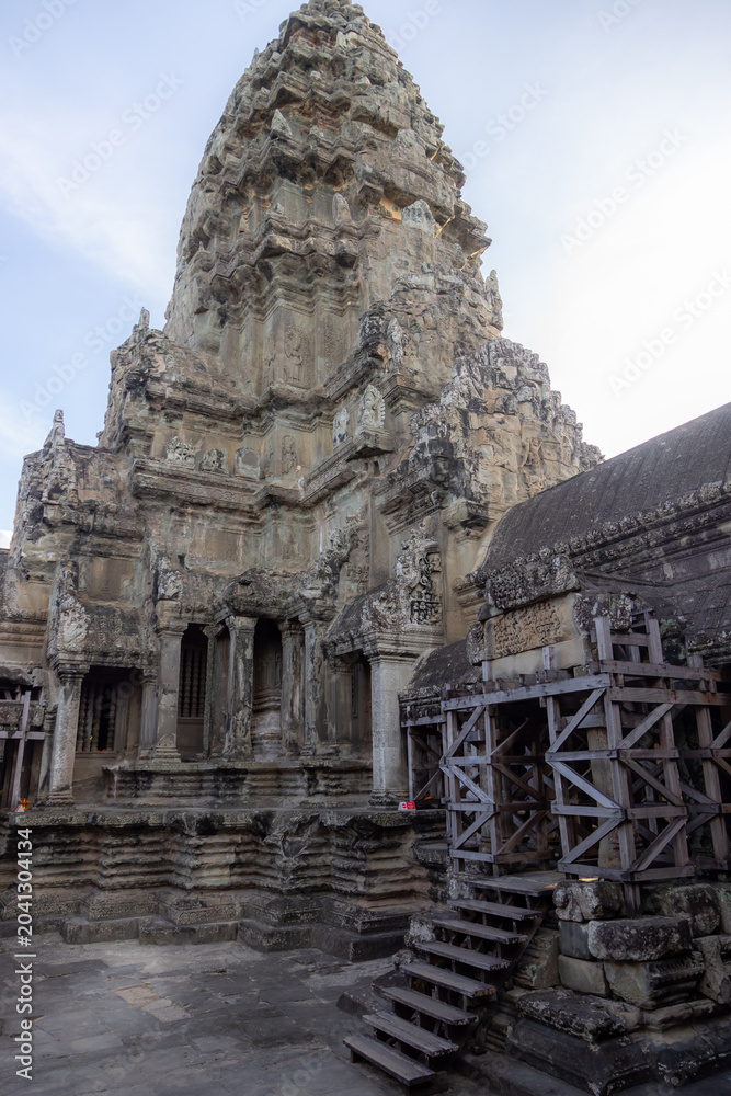 Naklejka premium Angkor Wat temple complex in Siem Reap, Cambodia, showcases intricate Khmer architecture and bas-reliefs, with scaffolding indicating ongoing restoration efforts.