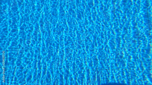 Sunlit Swimming Pool Water Surface with Blue Tiles and Ripple Reflection Pattern