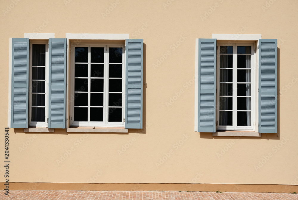 Obraz premium Traditional European building facade with elegant windows and blue wooden shutters