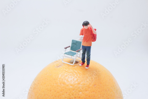 Miniature person standing beside chair on fruit
