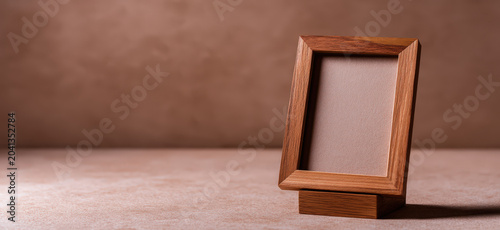 An empty wooden photo frame stands on a textured surface, its warm tones and simple design suggesting a space for cherished memories.