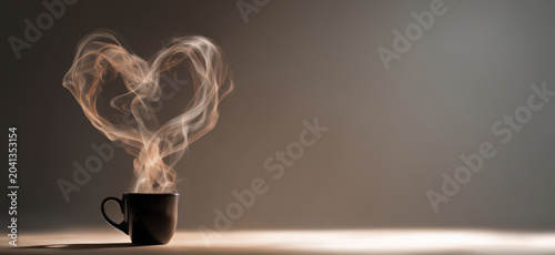 Steam rises from a dark mug, forming a heart shape in a symbolic representation of love and warmth, evoking a sense of comfort and affection.