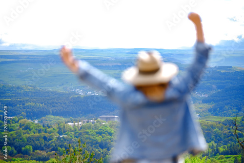 Obraz na plátne Out of focus back view of woman dreamer raising hands in front of valley scenery