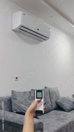 Turning off the air conditioner with a remote control, 9:16 vertical video, adjusting climate control, home comfort, stopping the cooling, modern HVAC system, lifestyle.