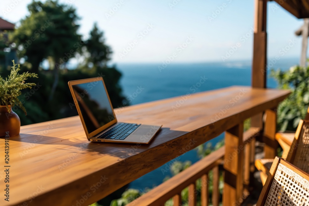Fototapeta premium Laptop computer on rustic wooden balcony with stunning ocean view work remote