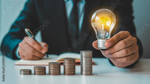 Business growth concept with coins and lightbulb on wooden table