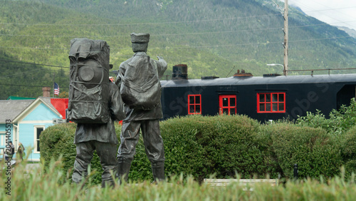 Foto Bronze statue of Klondike gold rush pioneers with vintage train car in Skagway, Alaska