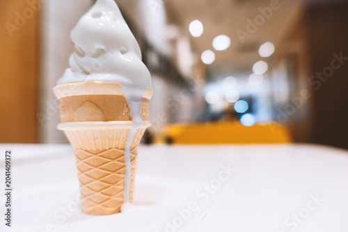 Vanilla Soft-Serve Ice Cream in Waffle Cone on White Table with Blurred Indoor Background