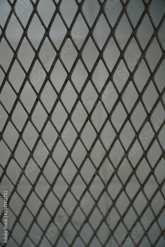 A close-up shot of the same expanded metal mesh or wire grid fence with an identical diamond/rhombus pattern