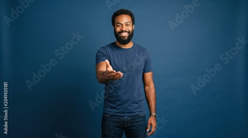 Friendly african american man gesturing towards camera welcoming against blue background with welcoming, inviting