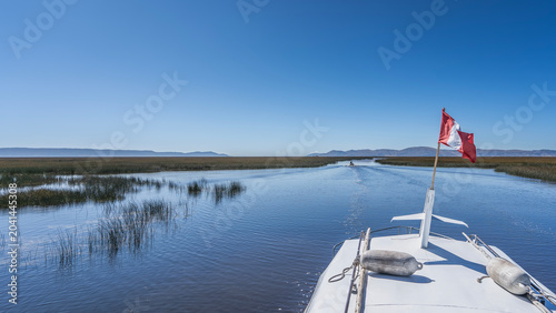 Tableau sur toile A boat is sailing on a high-altitude blue lake