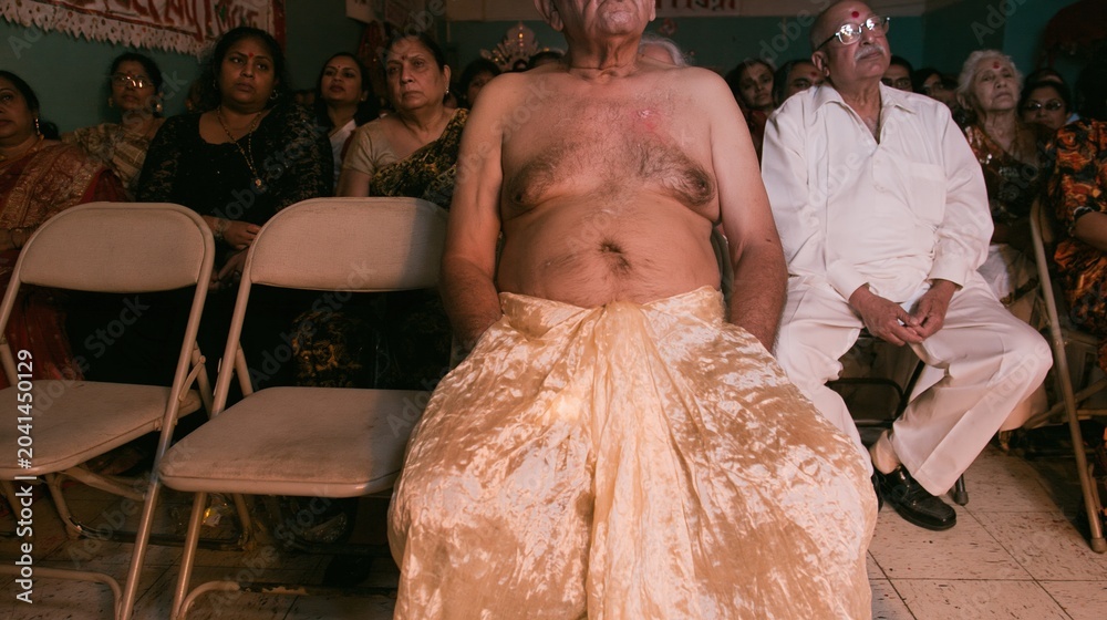 Fototapeta premium Senior man sitting on folding chairs during a community gathering for cultural journalism, holiday documentation and lifestyle anthropology in a communal hall